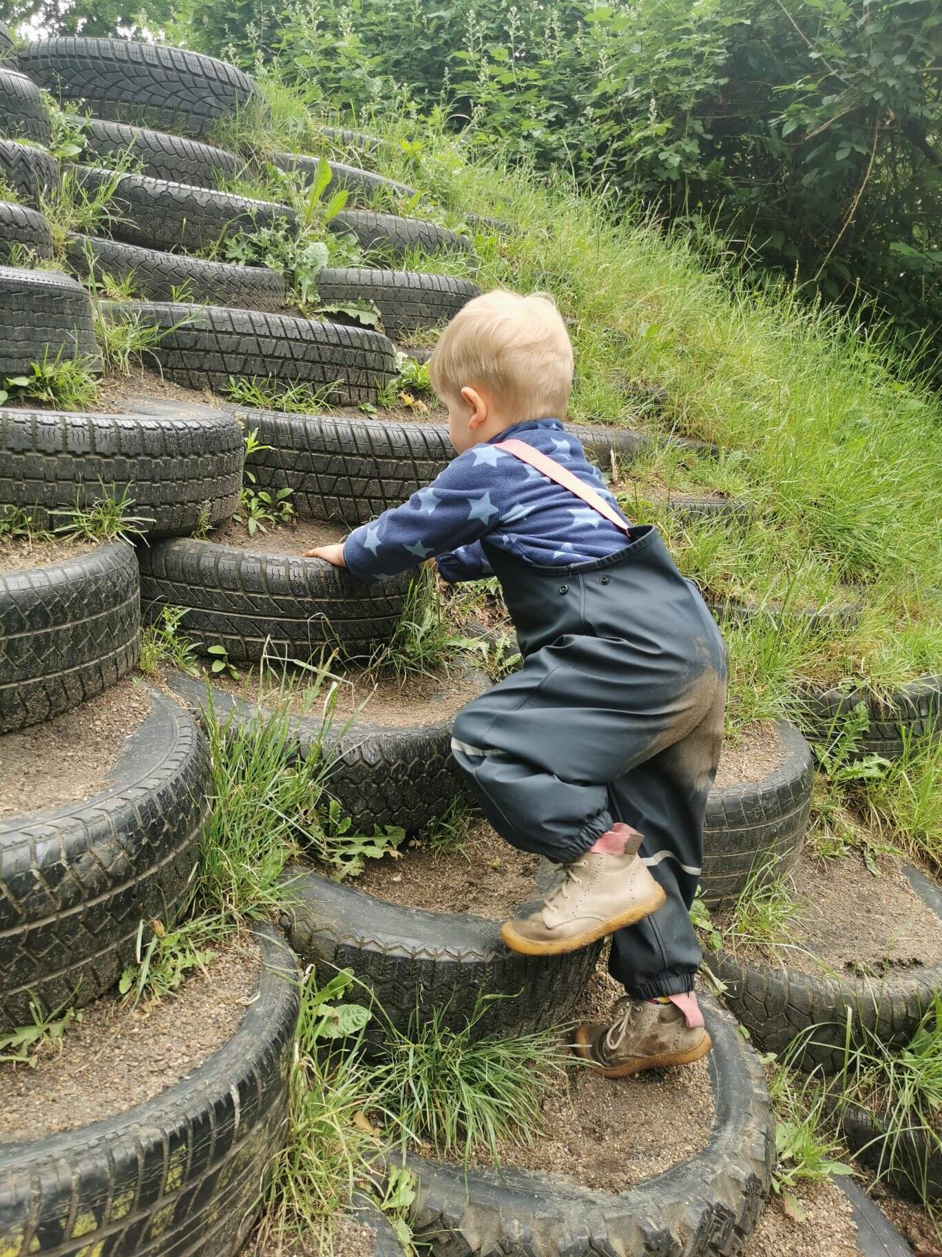Kind klettert auf Reifen-Treppe