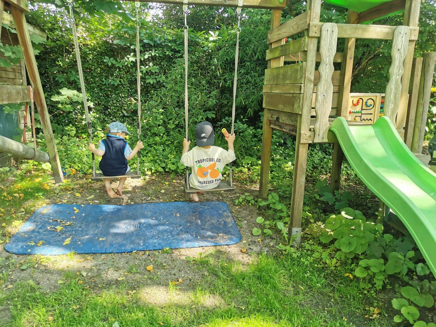 Zwei Kinder schaukeln im Garten